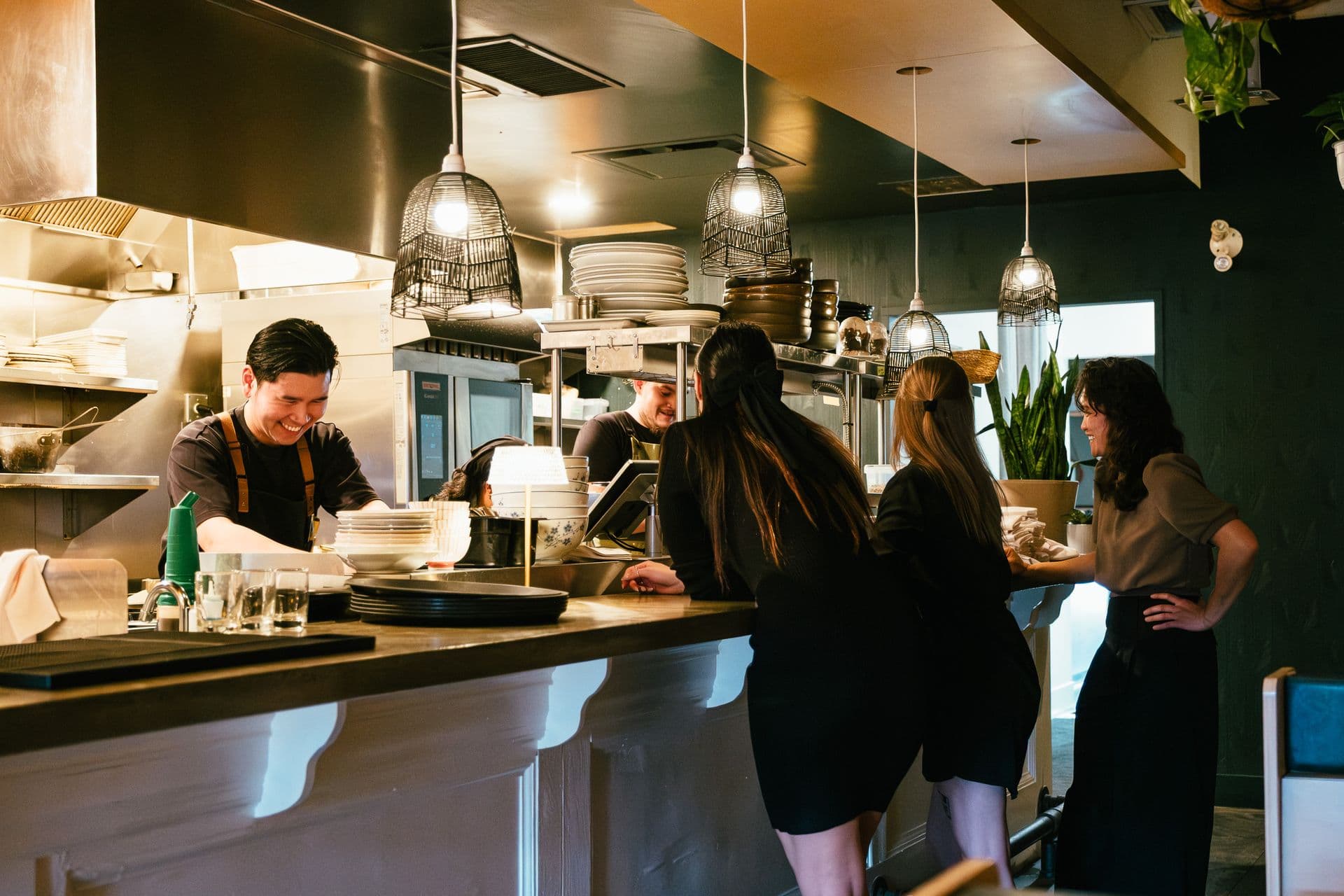 Kitchen staff working the pass of a small, busy restaurant.
