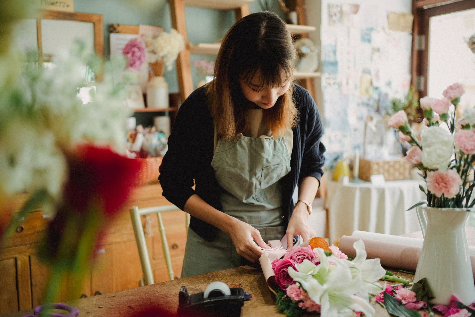 A florist arranging a bouquet behind the counter of her shop.