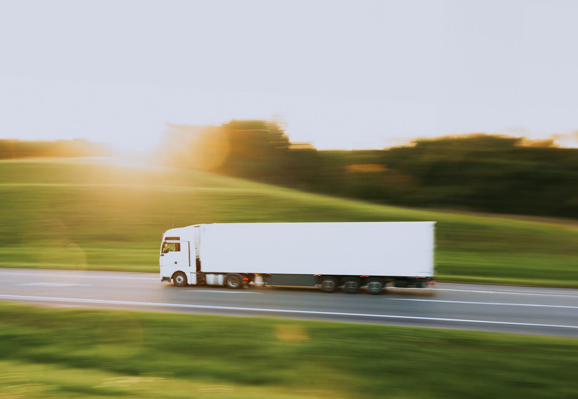 A delivery truck on the highway at sunset.
