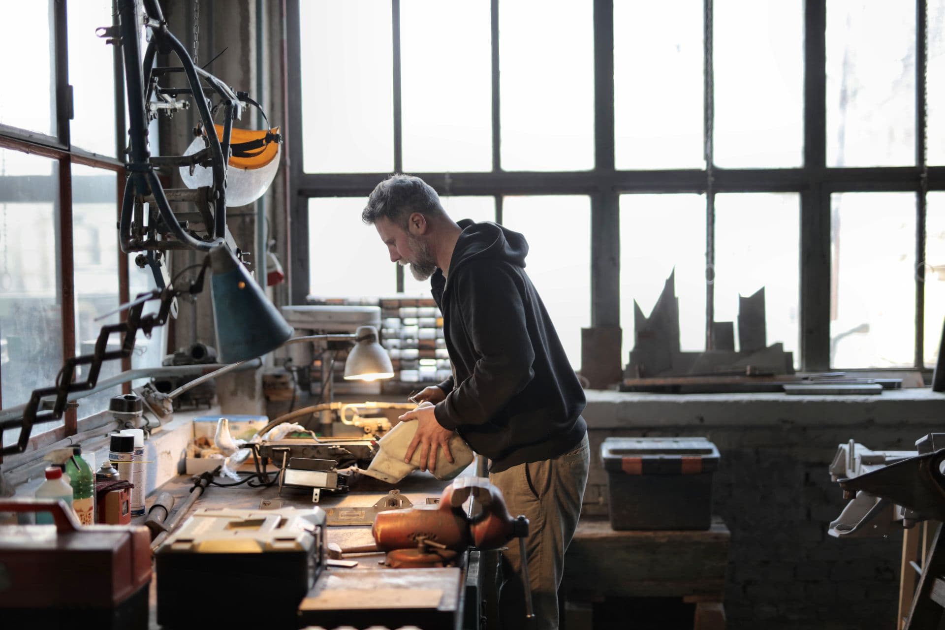 A tradesman working with metal tools at a bench in his workshop.